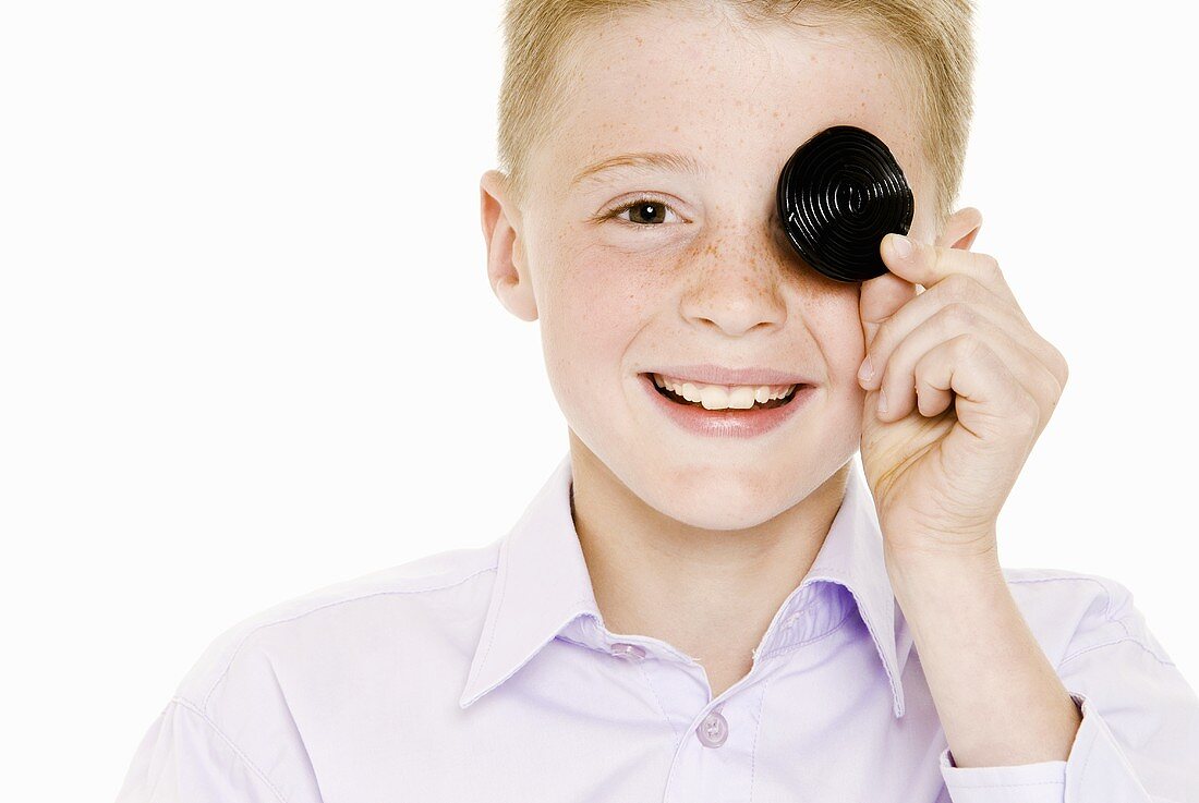 Boy covering one eye with a liquorice wheel