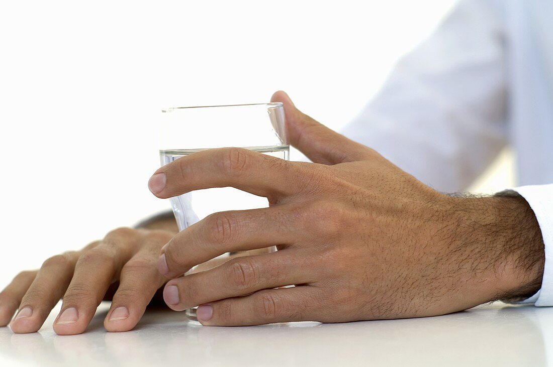 Männerhand hält ein Glas Wasser