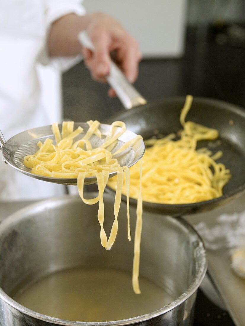 Putting tagliatelle into a frying pan