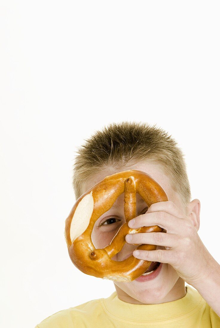 Boy holding a pretzel in front of his face