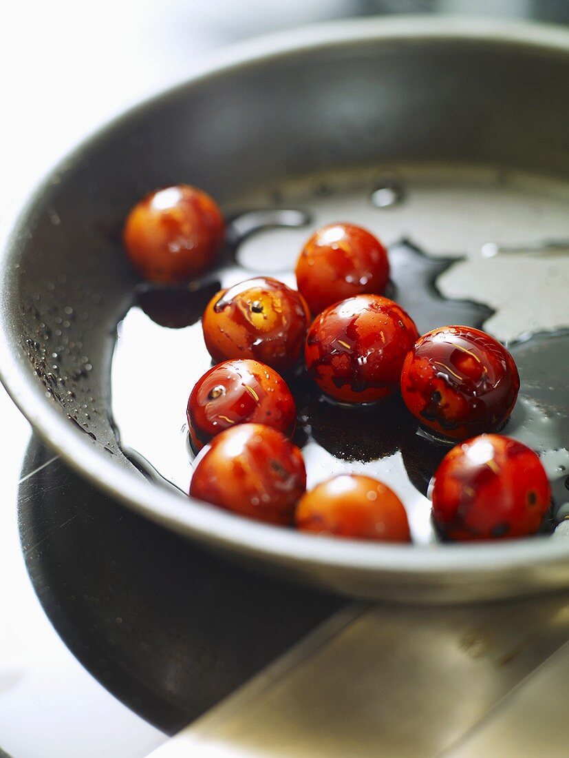 Frying cocktail tomatoes with balsamic vinegar in frying pan