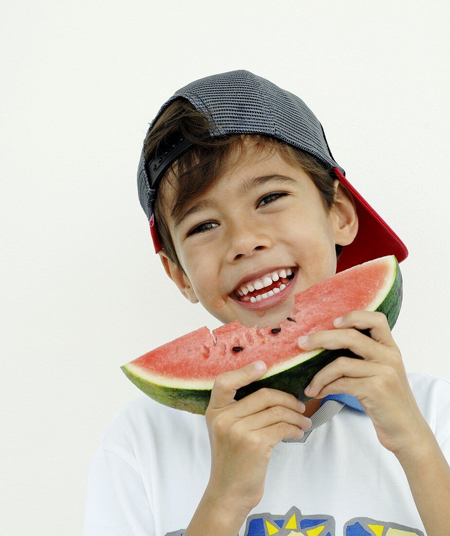 Boy holding a slice of watermelon with a bite taken