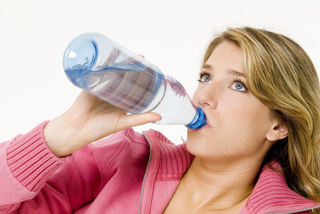 Junge Frau trinkt Wasser aus der Flasche