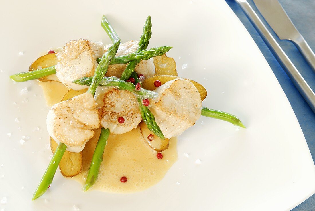 Scallops speared on asparagus with butter sauce