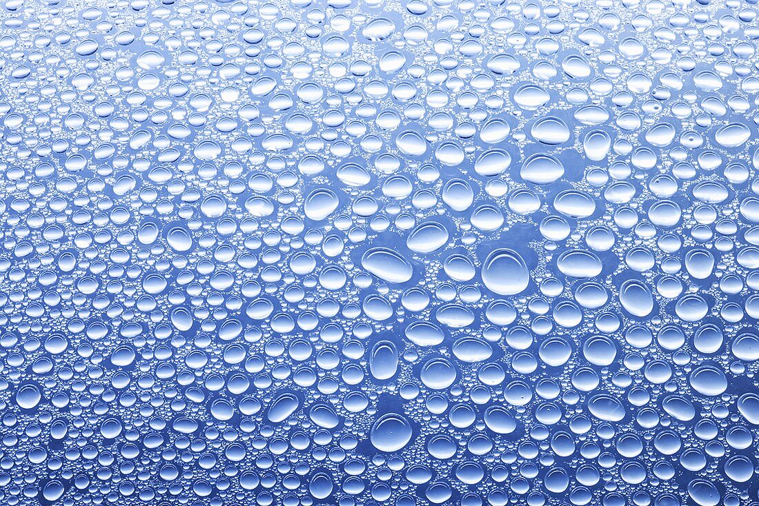 Drops of water on sheet of glass with blue background