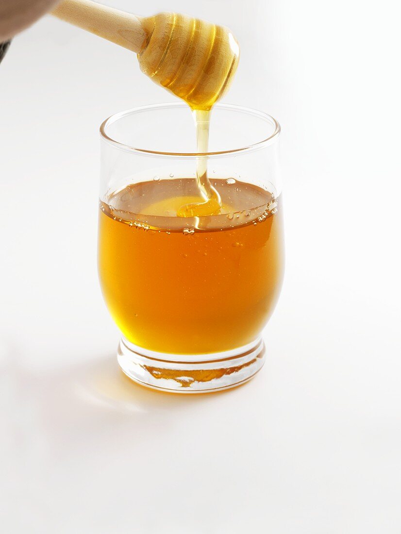 Honey in glass and on honey dipper