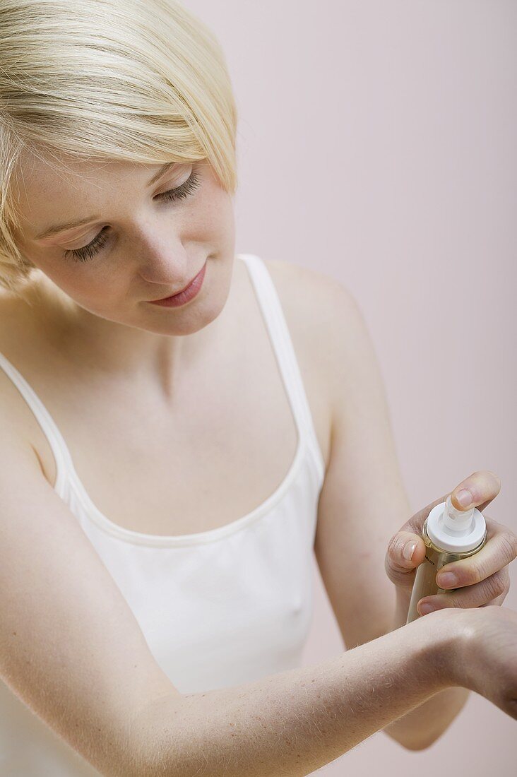 Young woman spraying perfume on her wrist