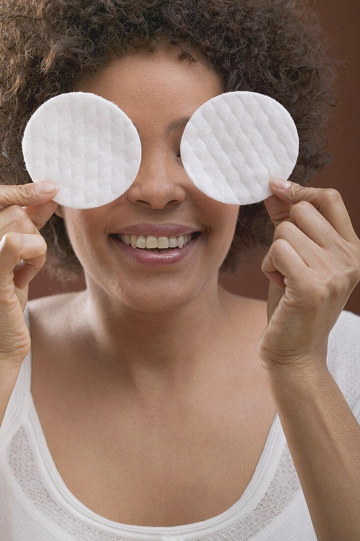 Young woman holding two cosmetic pads in front of her face
