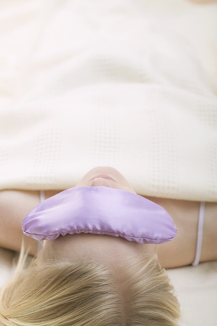 Young woman, lying down, with an eye pillow