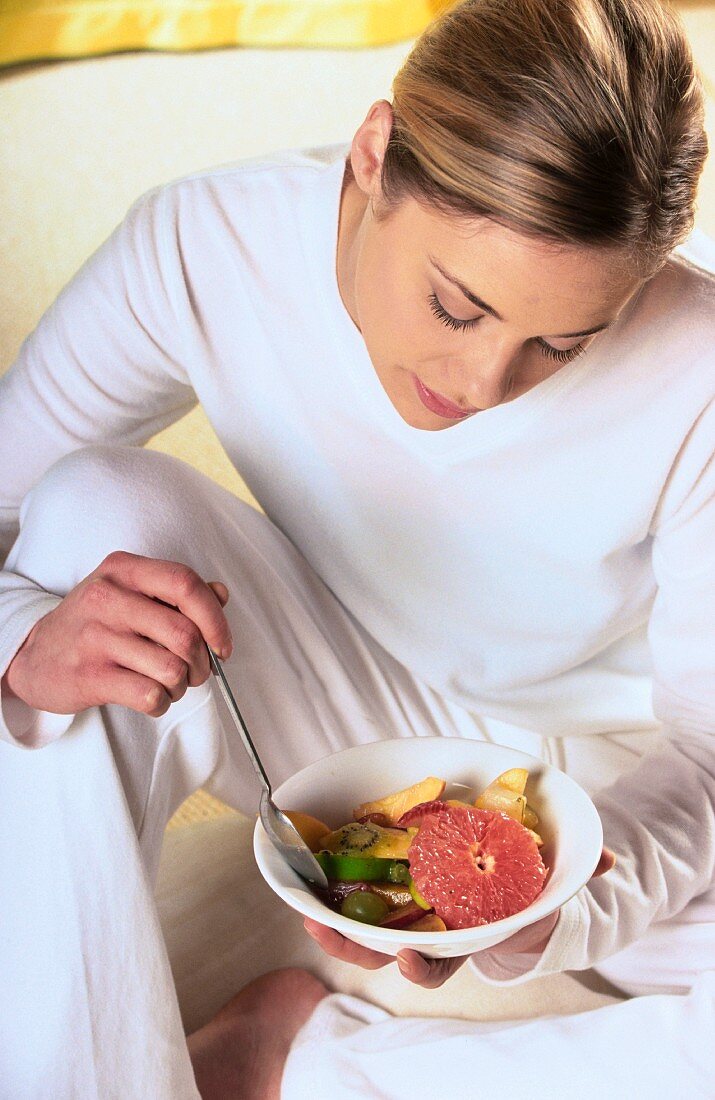 Gelangweilte Frau isst einen Obstsalat