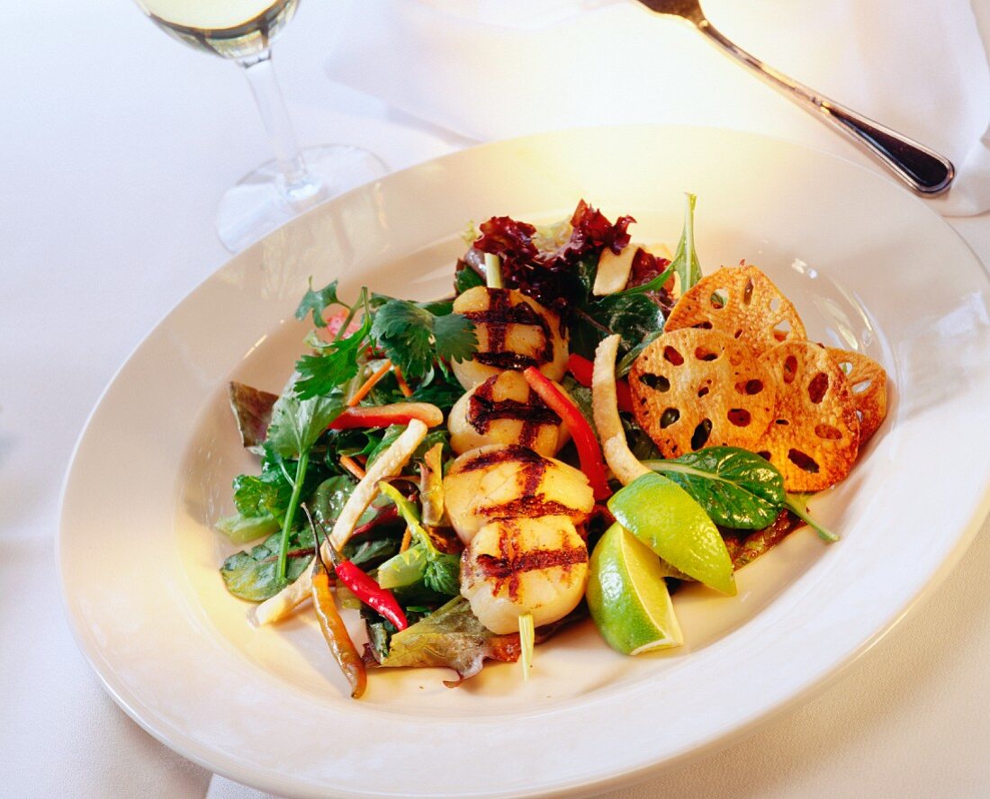 A scallop skewer, grilled, on a bed of salad