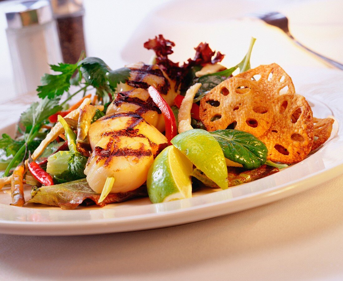 A skewer of scallops, grilled, with salad