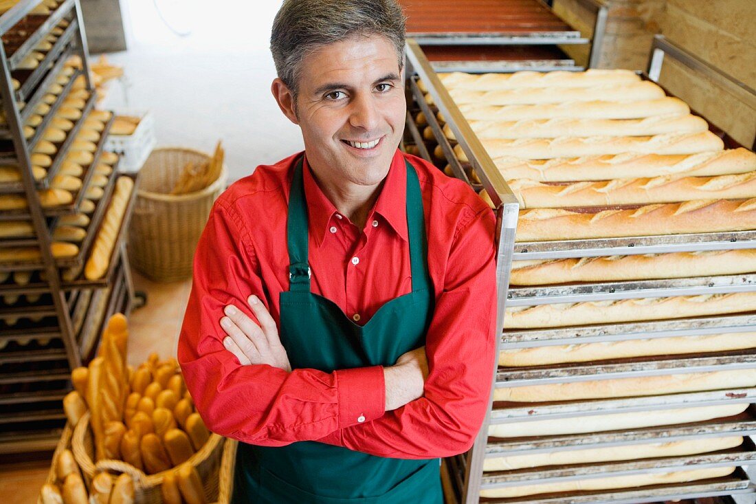 Baker in bakery with trays of baguettes
