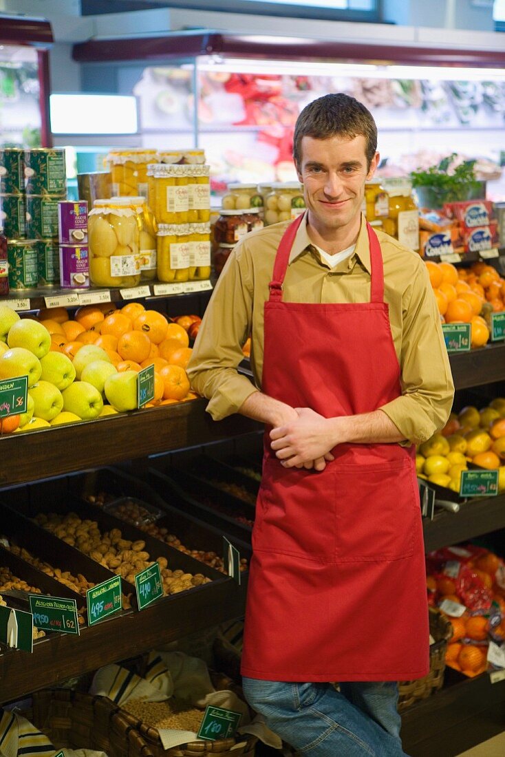 Sales assistant in front of shelves of fruit