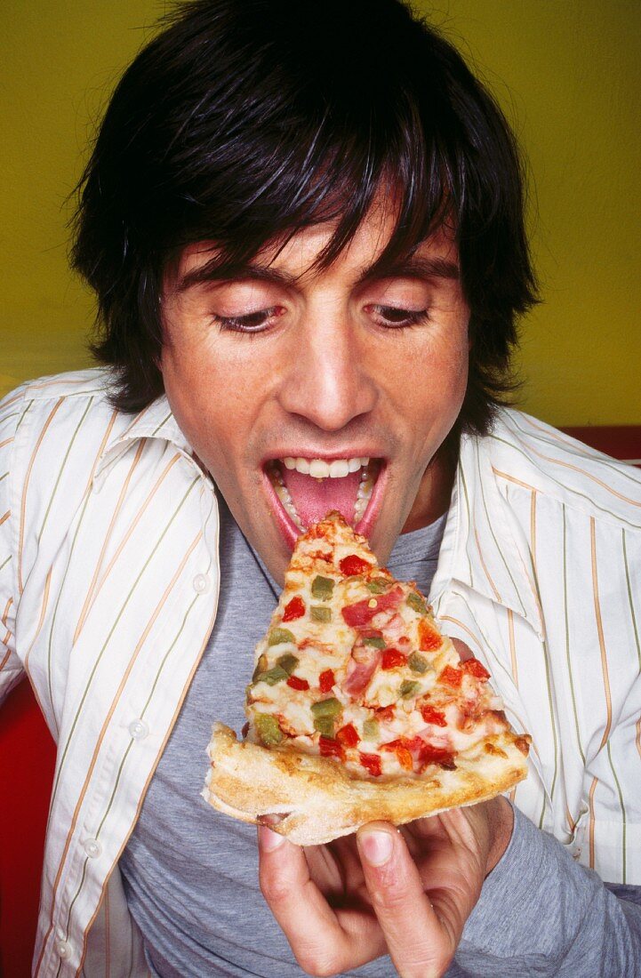 Mann isst ein Stück Pizza