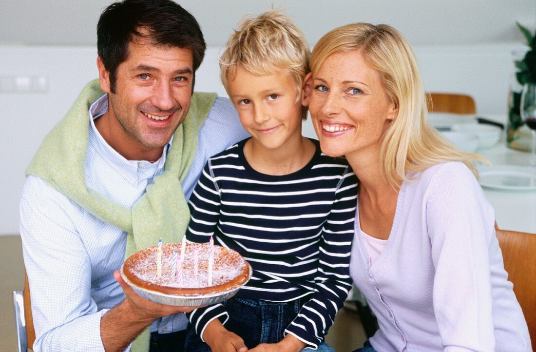 Father, mother and son celebrating birthday with cake