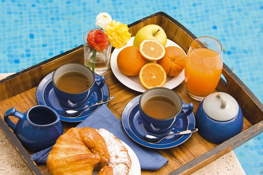 Ein Tablett mit Tee, Croissant und Orangensaft