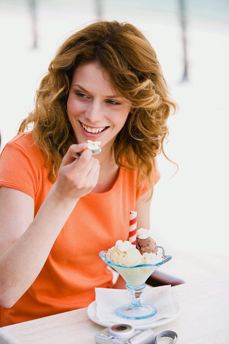 Woman eating ice-cream sundae in cafe