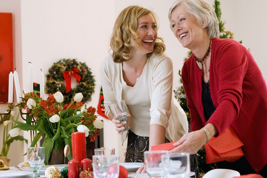 Frau mit Mutter beim Eindecken des Tisches zu Weihnachten