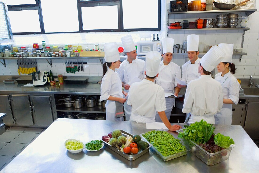 Trainee chefs learning to cook from a head chef