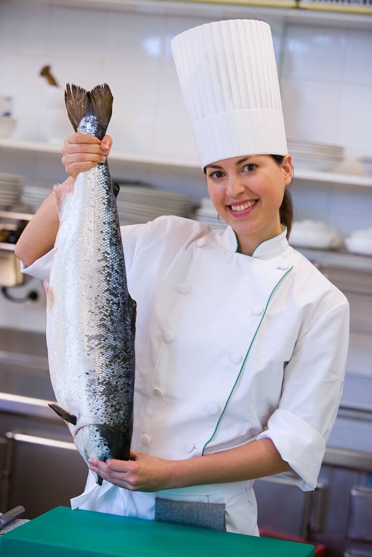 A chef holding up a whole fish