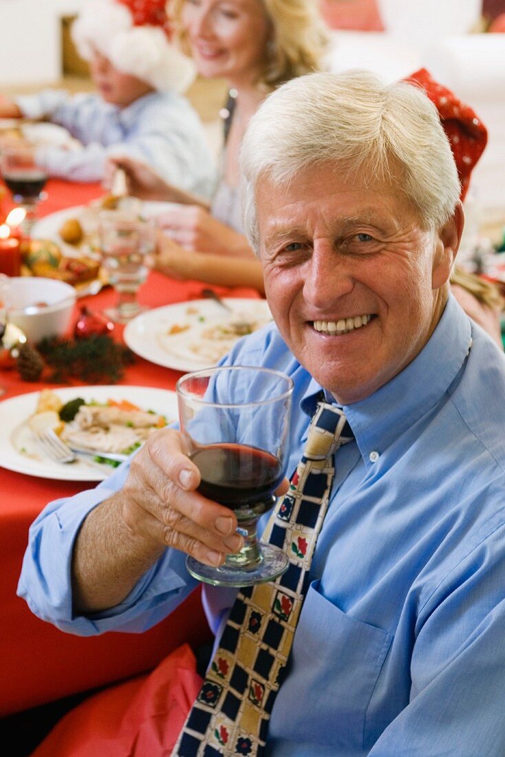 Grandfather at Christmas dinner with glass of red wine