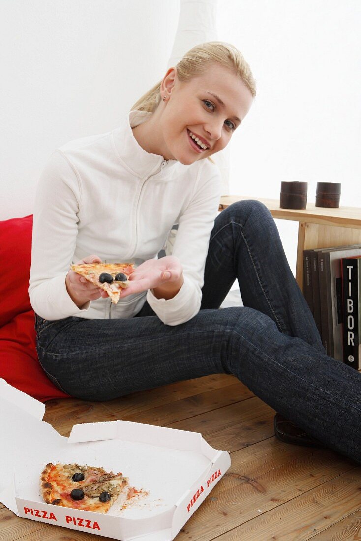 Seated woman eating pizza from pizza box