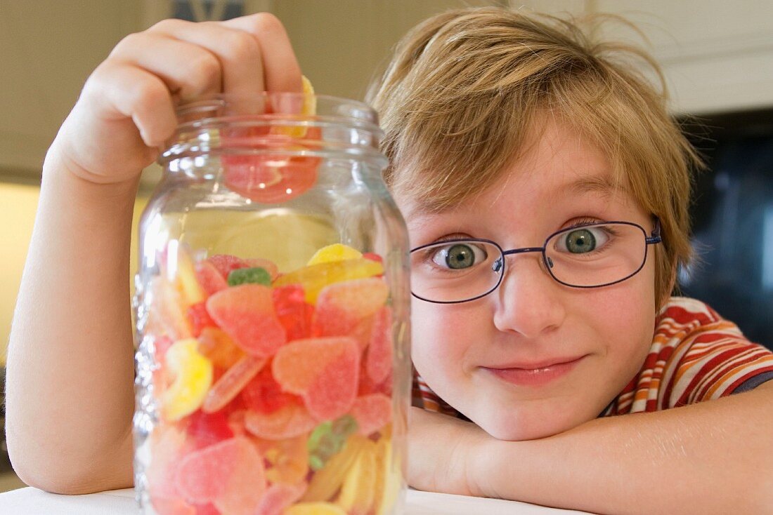 Junge beim Naschen von Fruchtgummi aus einem Glas