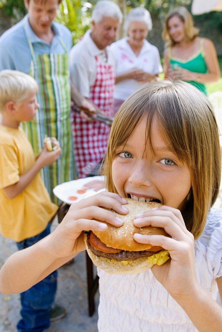 Mädchen beisst in einen ganzen selbstgemachten Hamburger