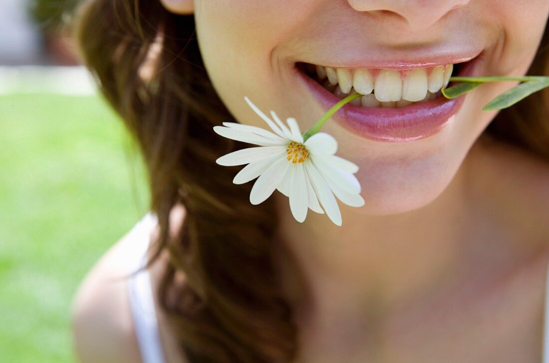 Woman with flower in mouth (close-up)