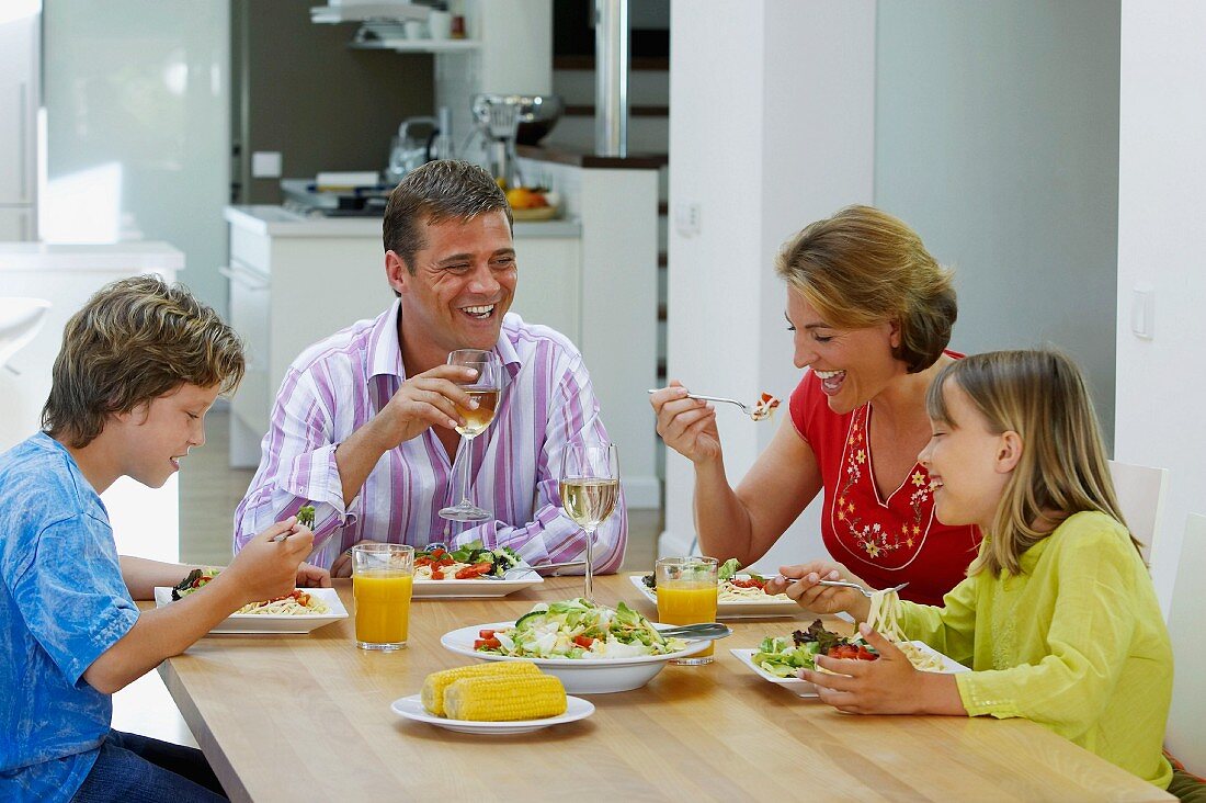 Familie beim Abendessen mit Salat und Nudeln