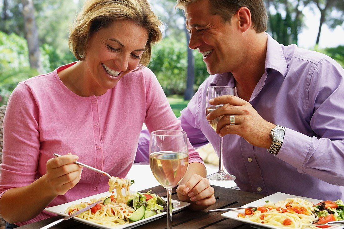 Paar beim Mittagessen mit Salat und Nudeln im Urlaub
