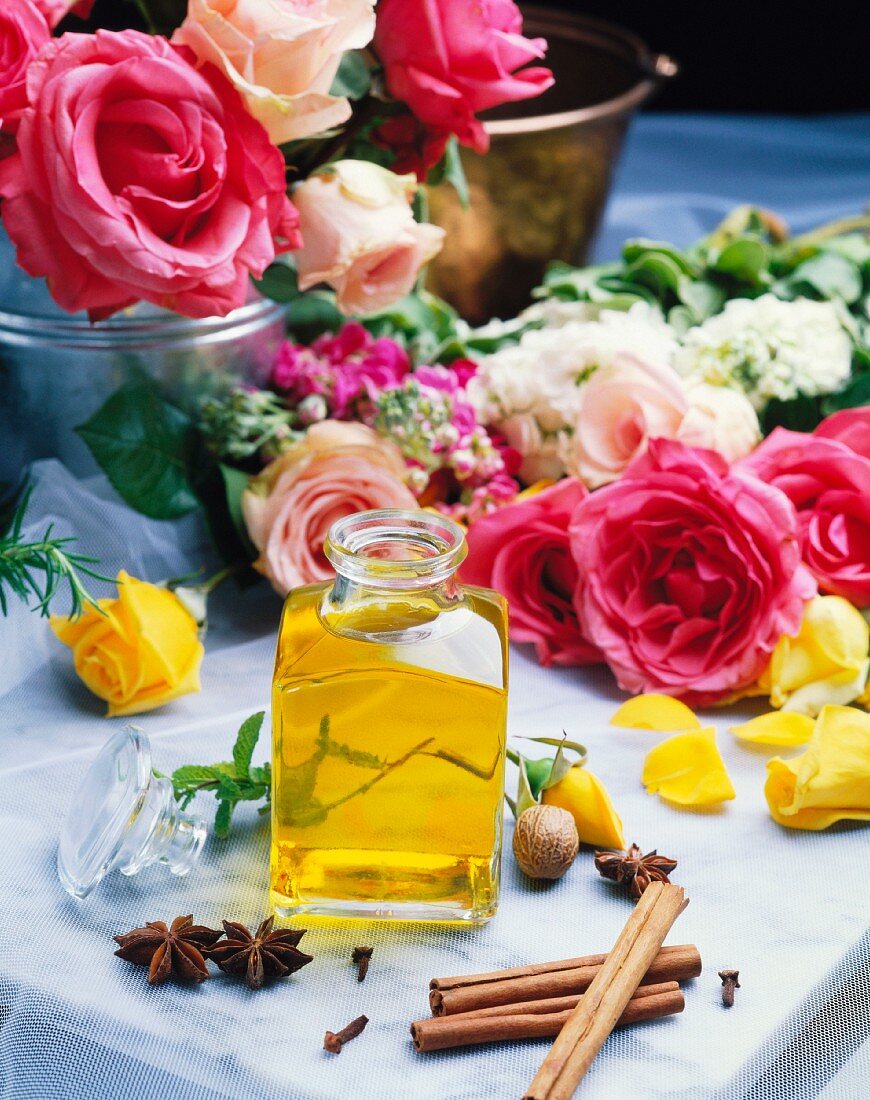 Still-life with a bottle of rose oil, roses and spices
