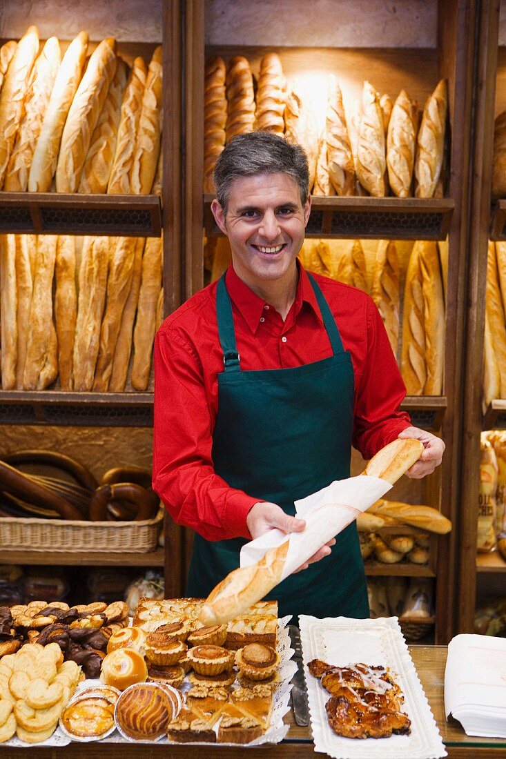 Shop assistant in bakery with pastries and baguettes