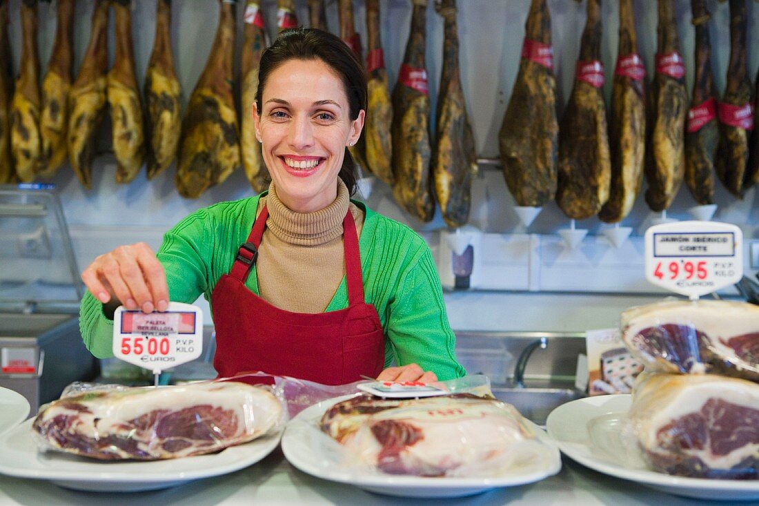 Shop assistant with Serrano ham in butcher's shop