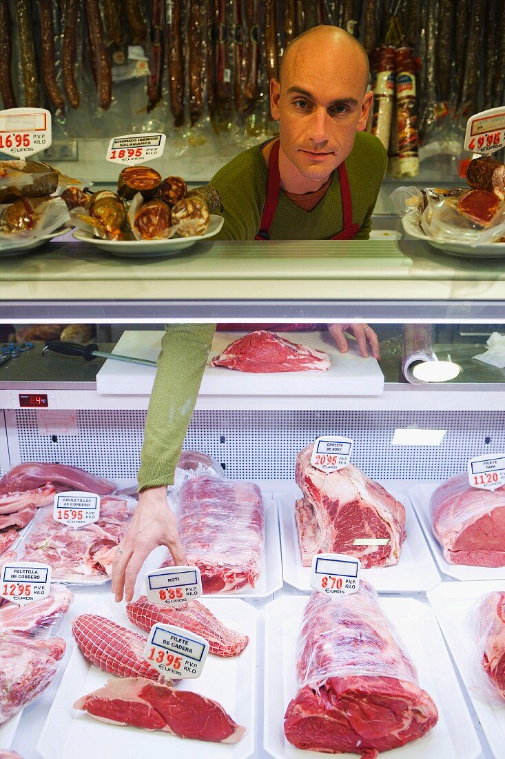 Shop assistant behind counter of butcher's shop