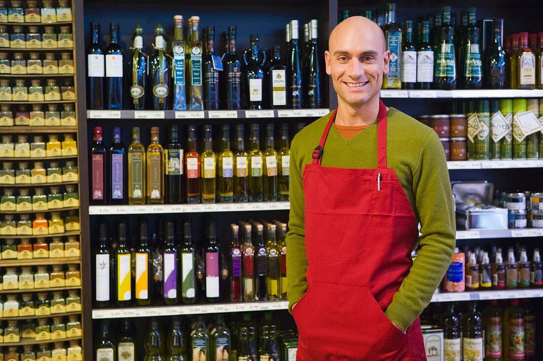 Sales assistant in supermarket in front of shelves of oil and vinegar