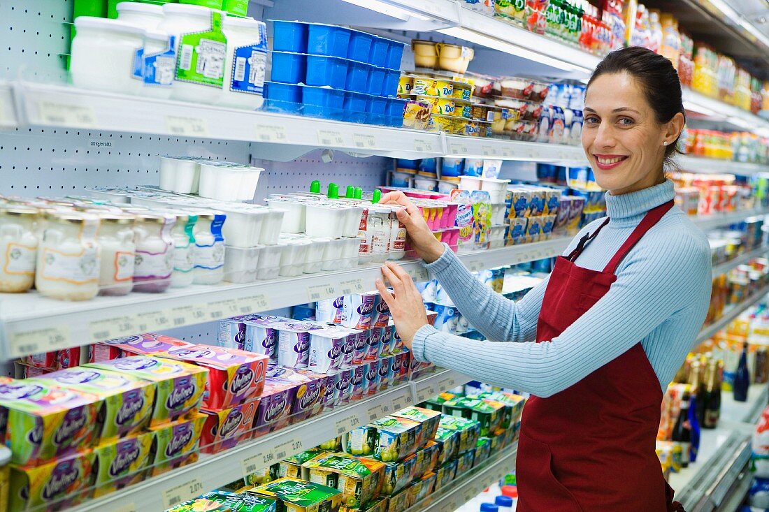 Shop assistant in front of chiller cabinets of dairy products