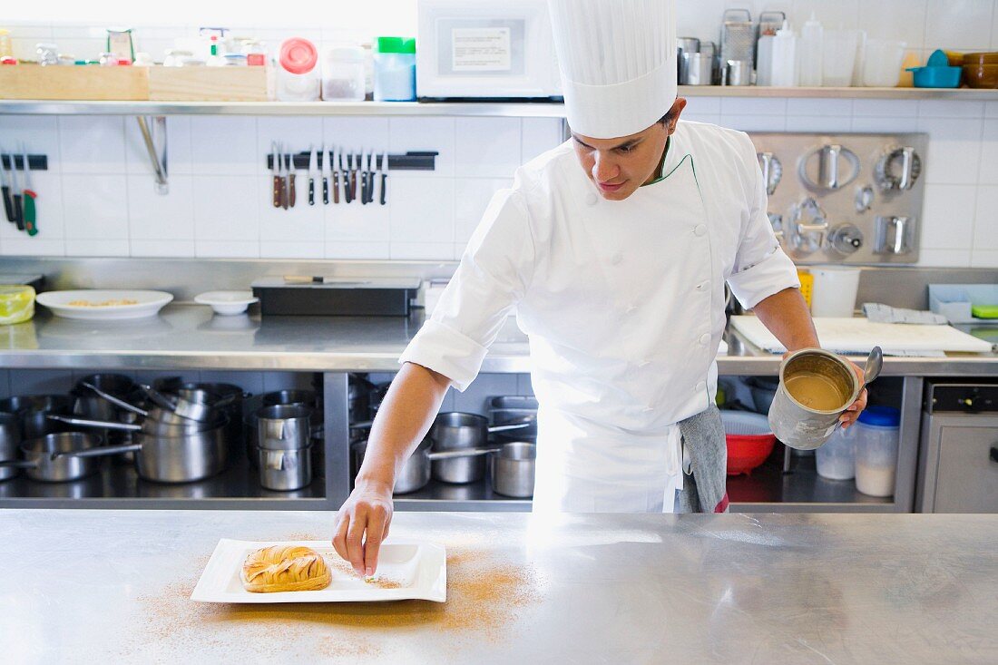 A chef in a commercial kitchen arranging food on a plate