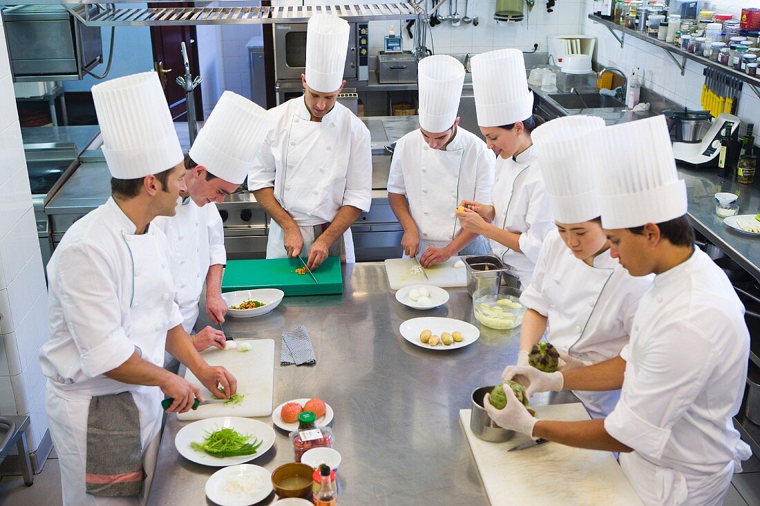 A head chef with trainee chefs in a commercial kitchen