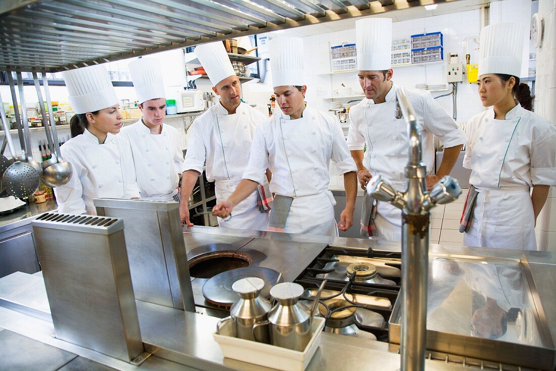 A head chef and trainee chefs in a commercial kitchen