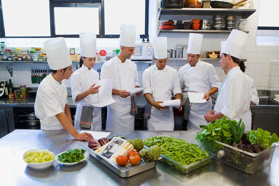 Chefs with orders and vegetables in a commercial kitchen