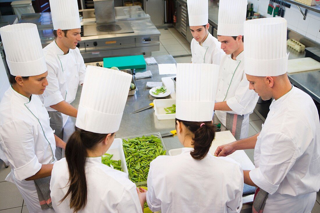 Chefs podding peas in a commercial kitchen