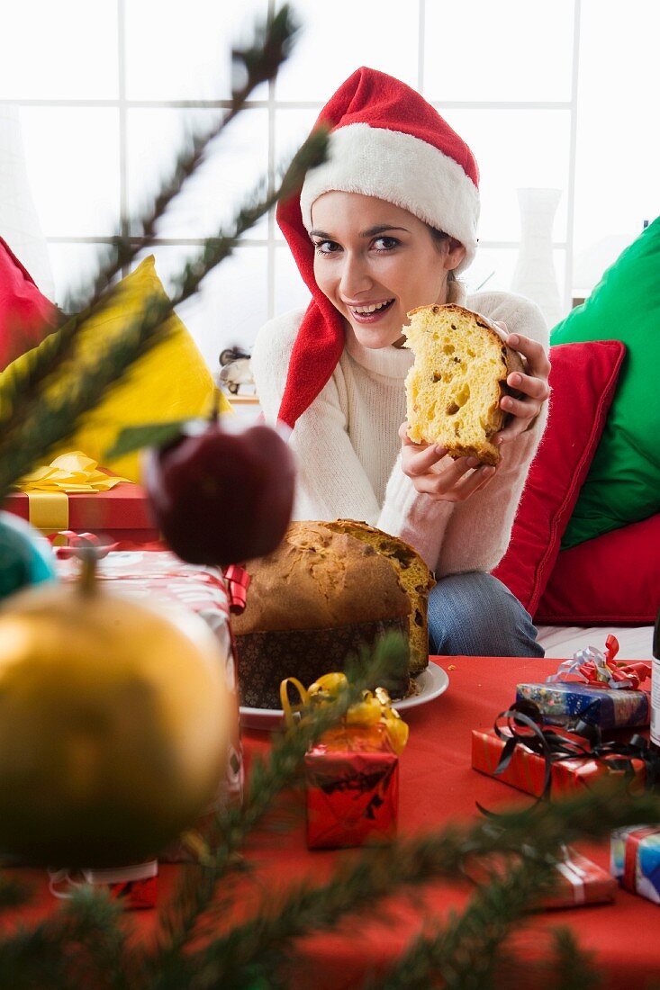 Woman wearing Father Christmas hat holding panettone