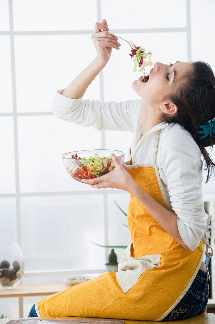 Woman eating lettuce from a bowl of salad