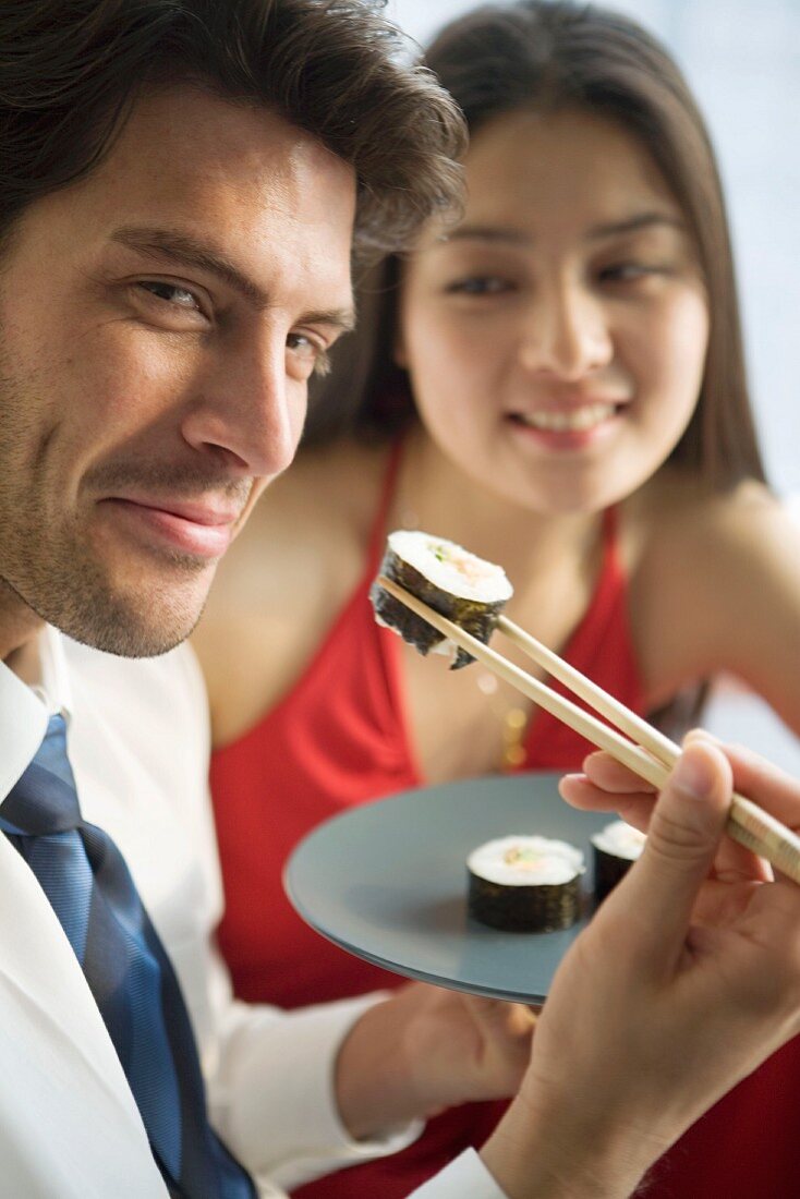 Mann isst Sushi mit Essstäbchen