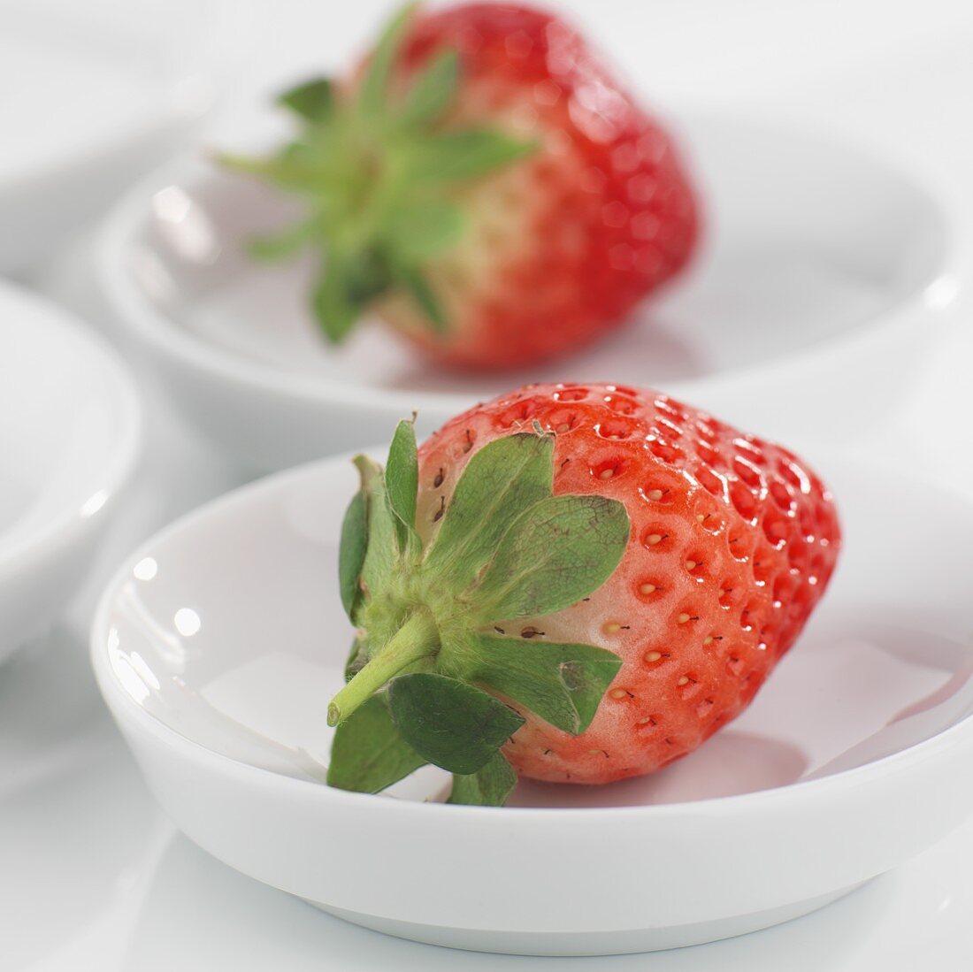 Whole strawberries in small white dishes