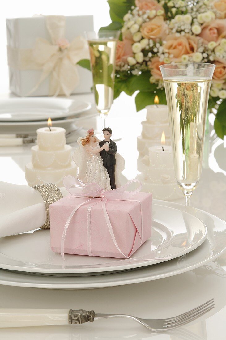 Wedding place-setting: gift, bride & groom figures, glass of wine