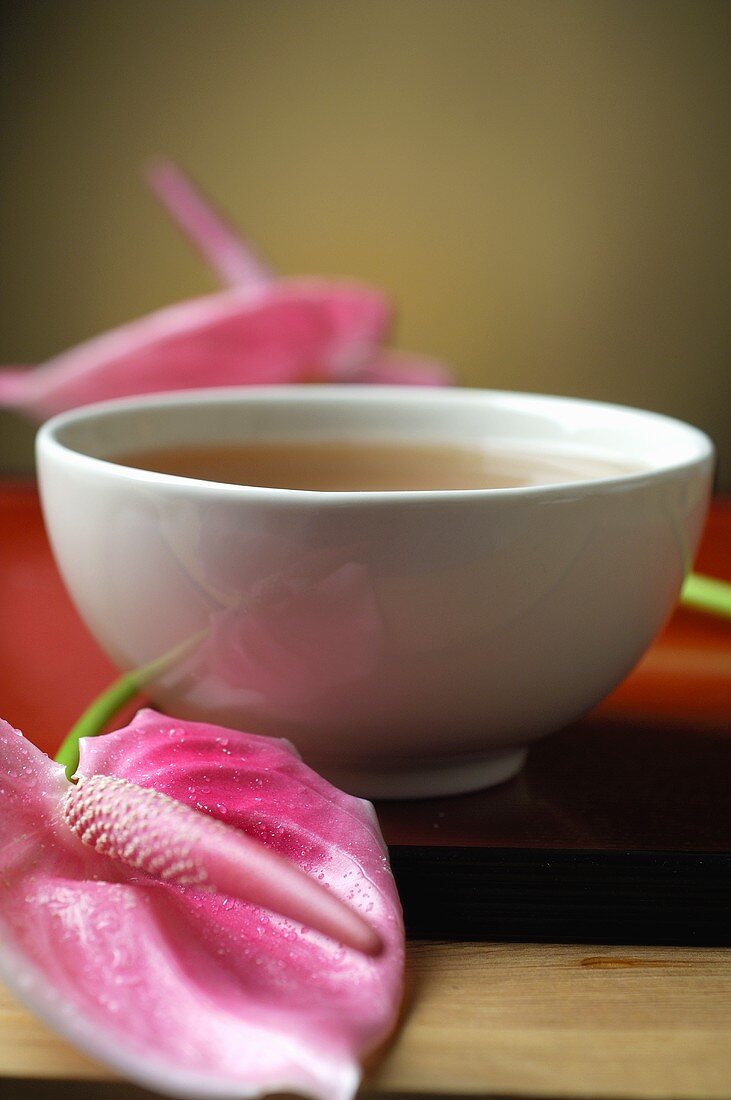 Bowl of tea and pink flamingo lily
