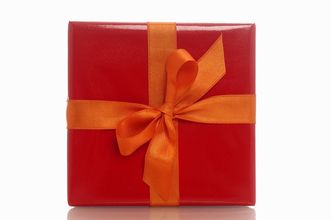 Geschenk mit rotem Geschenkpapier und oranger Schleife